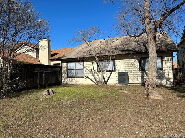 back of house with central air condition unit and a yard