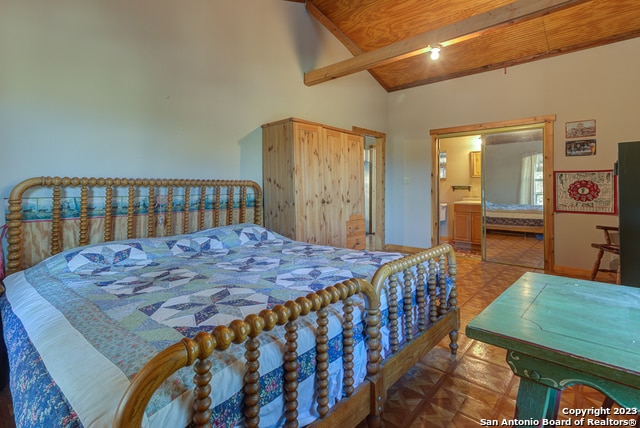 tiled bedroom featuring connected bathroom, high vaulted ceiling, and beamed ceiling