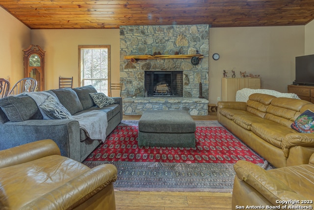 living room featuring a fireplace, wood ceiling, and wood-type flooring