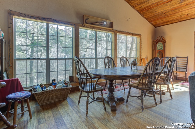 dining area with a wealth of natural light, vaulted ceiling, wooden ceiling, and light hardwood / wood-style flooring