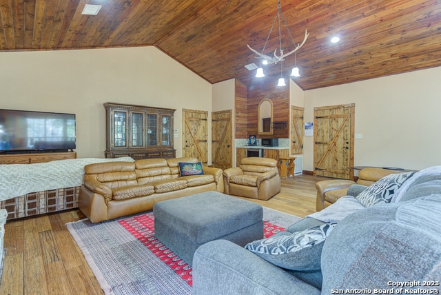 living room with high vaulted ceiling, light hardwood / wood-style floors, wood ceiling, and a chandelier