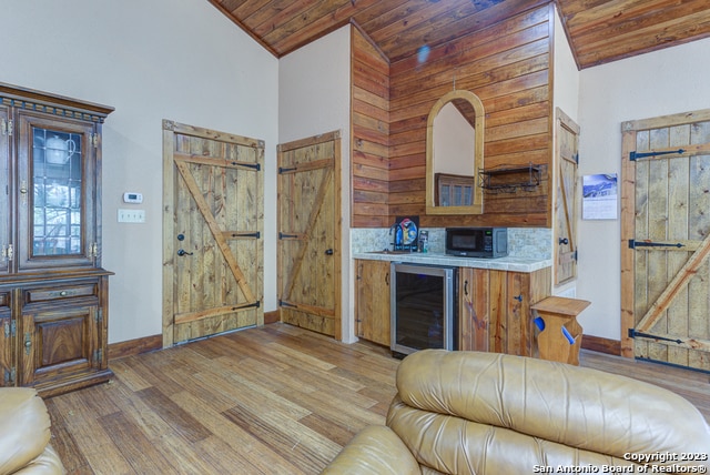 kitchen featuring wooden walls, wood ceiling, beverage cooler, a barn door, and hardwood / wood-style flooring