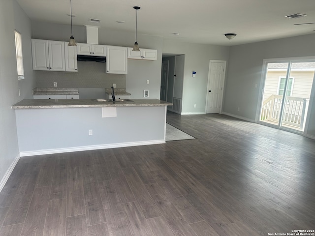 kitchen with white cabinets, dark hardwood / wood-style floors, sink, light stone countertops, and hanging light fixtures