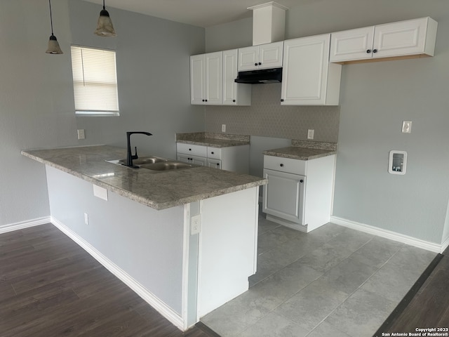 kitchen with decorative light fixtures, sink, kitchen peninsula, and white cabinets