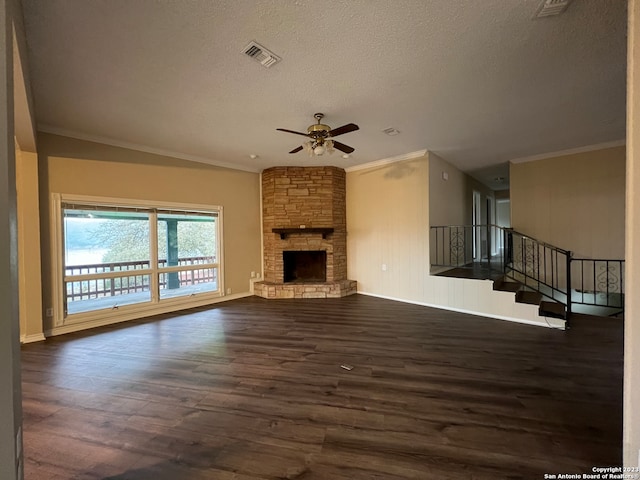 119 Cedar Tree Ln, Canyon Lake, TX 78133 - unfurnished living room featuring dark wood-type flooring, ceiling fan, a textured ceiling, a stone fireplace, and crown molding