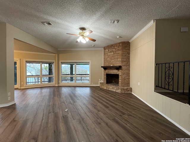 119 Cedar Tree Ln, Canyon Lake, TX 78133 - unfurnished living room featuring ornamental molding, ceiling fan, dark wood-type flooring, and a stone fireplace