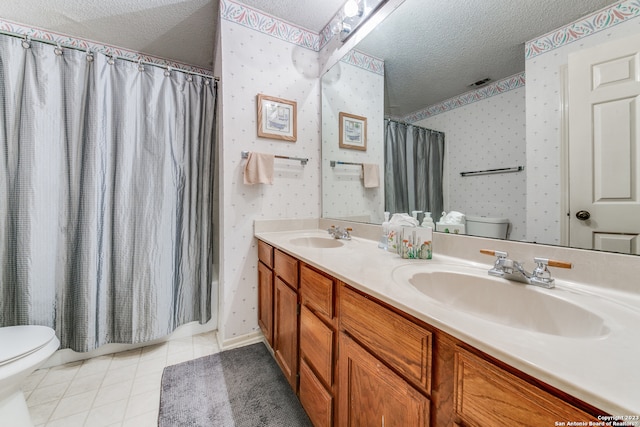 bathroom featuring toilet, tile floors, dual sinks, oversized vanity, and a textured ceiling