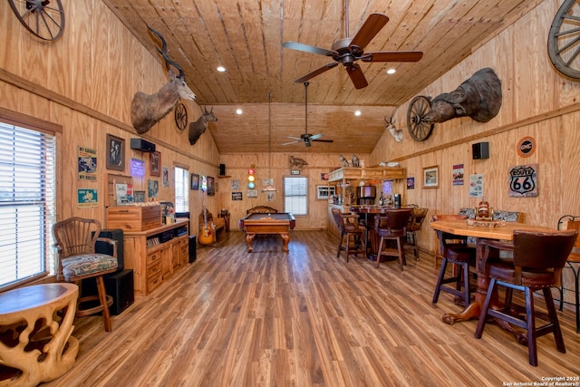 interior space featuring wooden walls, ceiling fan, wood ceiling, wood-type flooring, and high vaulted ceiling