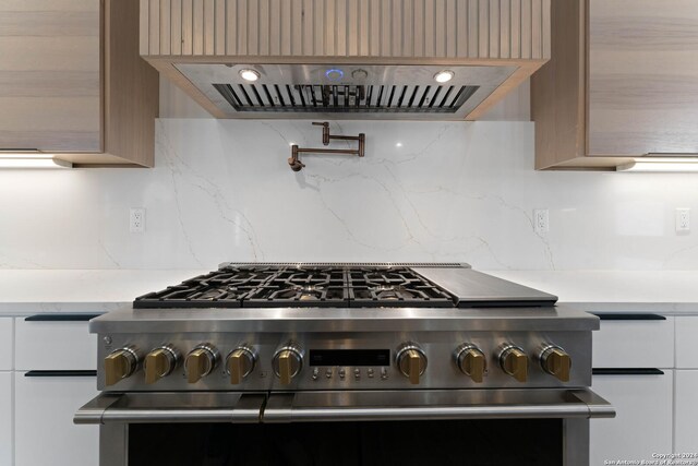 kitchen with high end stainless steel range oven, exhaust hood, backsplash, and light brown cabinets