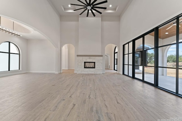 unfurnished living room with a fireplace, a high ceiling, and light wood-type flooring