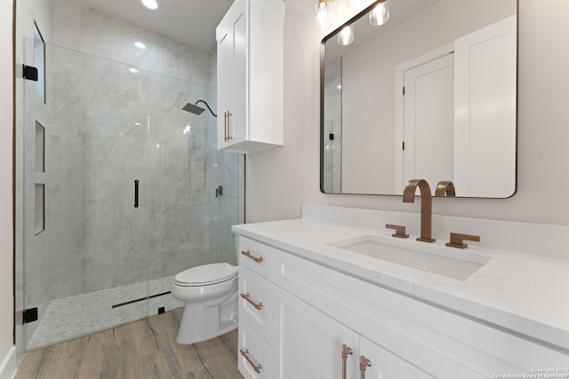 bathroom with vanity, hardwood / wood-style flooring, toilet, and a shower with shower door