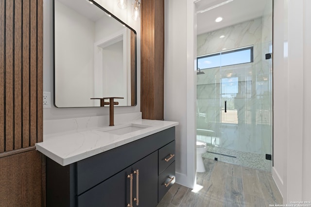 bathroom with hardwood / wood-style floors, vanity, toilet, and a shower with door