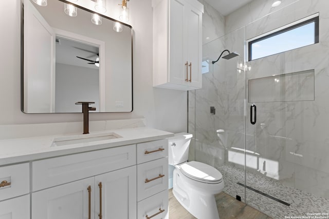 bathroom with vanity, a shower with door, ceiling fan, hardwood / wood-style floors, and toilet