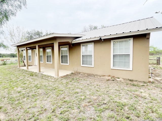 rear view of house with a lawn and a patio