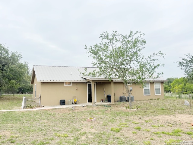 rear view of house featuring a lawn and central air condition unit