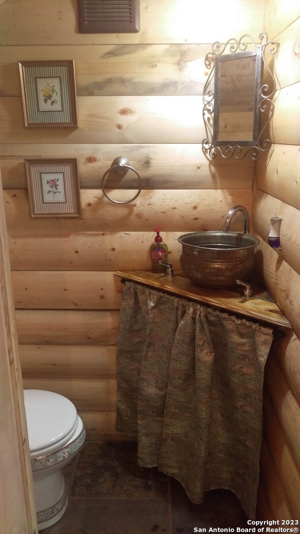 bathroom featuring rustic walls and toilet