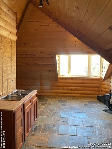 interior space with dark tile floors, lofted ceiling, log walls, and wood ceiling