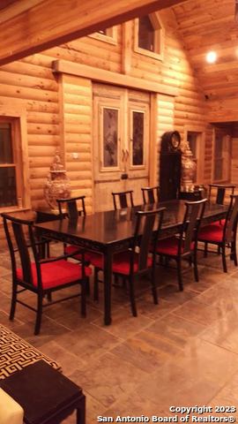 dining area with log walls, high vaulted ceiling, tile flooring, and wood ceiling