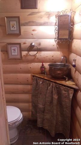 bathroom with log walls and toilet