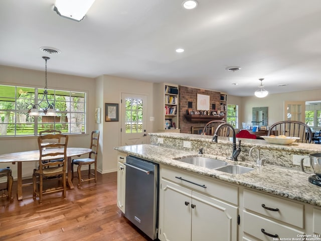 kitchen with pendant lighting, a brick fireplace, hardwood / wood-style floors, white cabinets, and dishwasher