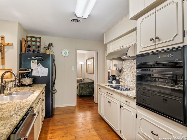 kitchen with white cabinets, light hardwood / wood-style flooring, black appliances, and sink