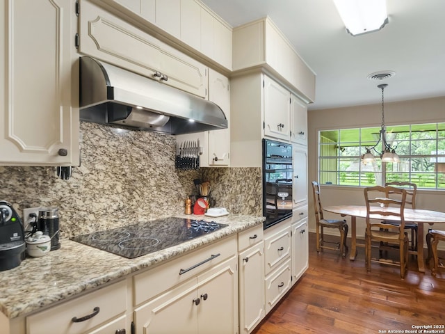 kitchen featuring light stone countertops, decorative light fixtures, backsplash, and black appliances