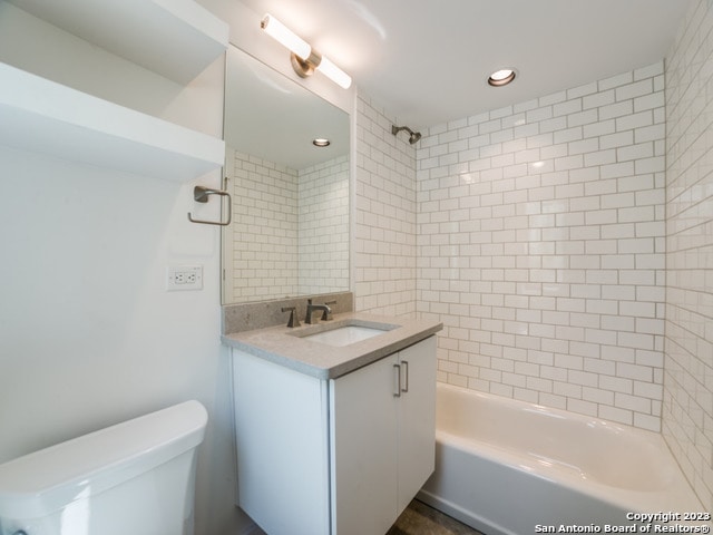 full bathroom featuring tiled shower / bath combo, toilet, and vanity