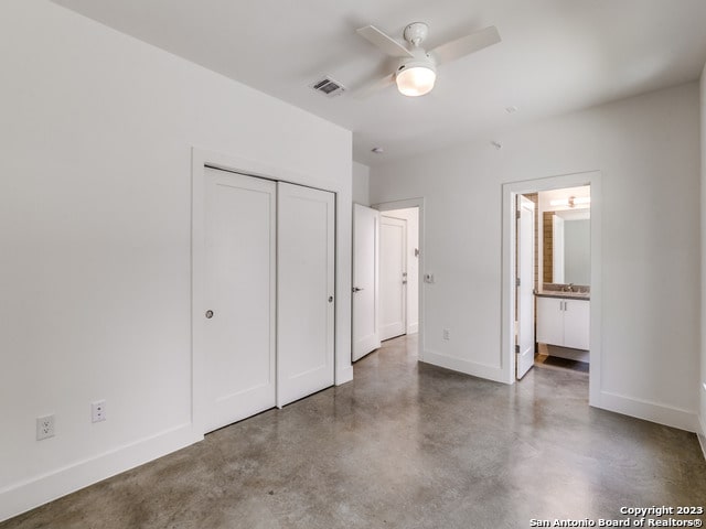 unfurnished bedroom with ensuite bathroom, a closet, concrete flooring, and ceiling fan