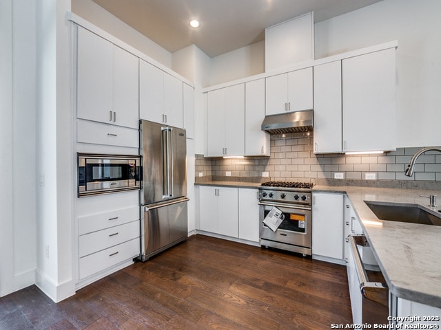 kitchen with dark hardwood / wood-style flooring, high quality appliances, white cabinetry, and sink