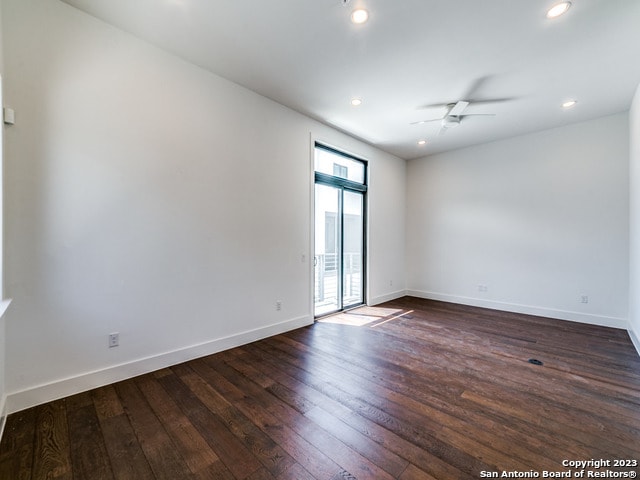 empty room with ceiling fan and dark wood-type flooring