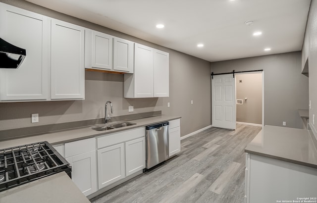 kitchen with stainless steel dishwasher, light hardwood / wood-style floors, sink, a barn door, and white cabinets