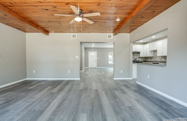 unfurnished living room featuring wood-type flooring, wooden ceiling, ceiling fan, and beamed ceiling