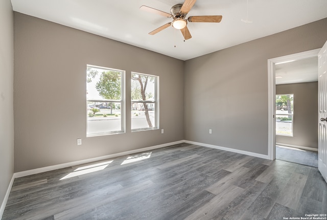 spare room featuring plenty of natural light, ceiling fan, and dark hardwood / wood-style flooring