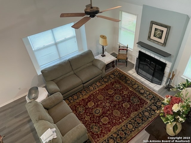 living room with a tile fireplace, light hardwood / wood-style floors, and ceiling fan