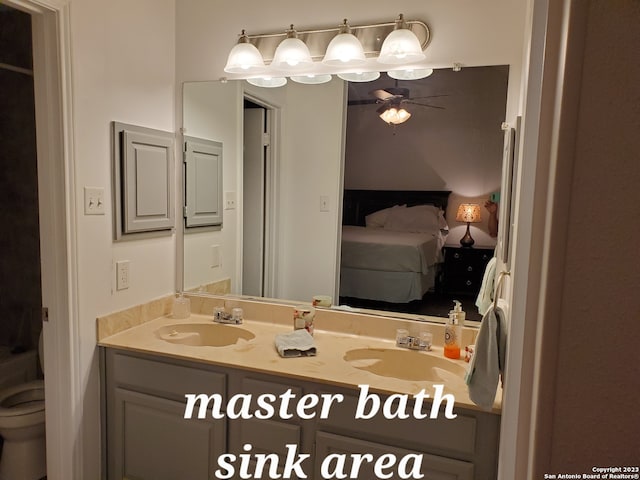 bathroom with dual sinks, ceiling fan, and vanity with extensive cabinet space