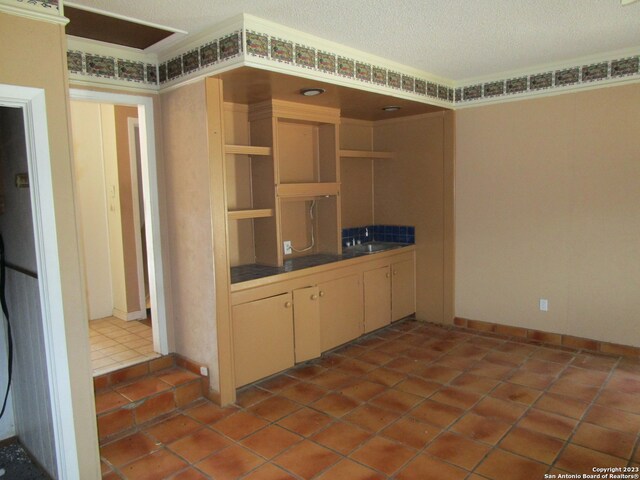 interior space featuring cream cabinets, tile flooring, and a textured ceiling