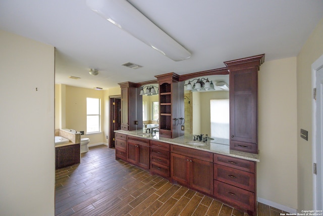 kitchen with dark wood-type flooring, light stone counters, ornate columns, and sink