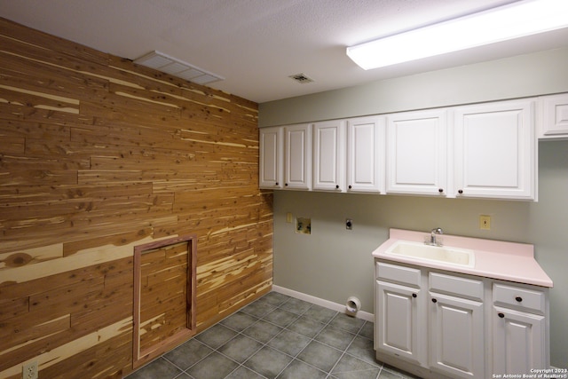 washroom featuring sink, hookup for a washing machine, dark tile patterned flooring, and wooden walls