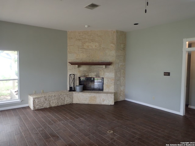 unfurnished living room featuring a stone fireplace and dark wood-type flooring