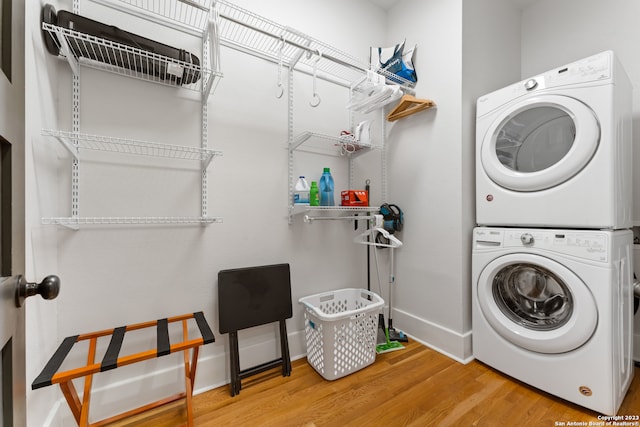 clothes washing area with stacked washing maching and dryer and light wood-type flooring