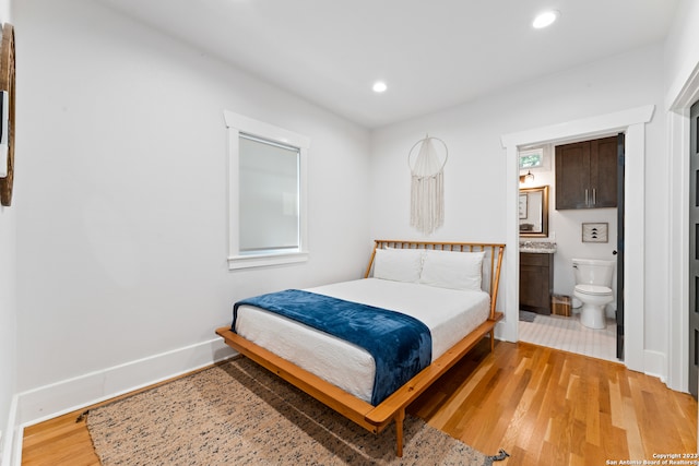 bedroom with ensuite bathroom and light tile flooring