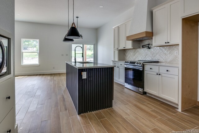 kitchen featuring custom range hood, stainless steel range with electric cooktop, and white cabinets