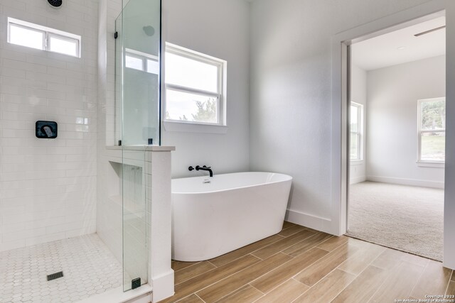 bathroom featuring shower with separate bathtub and wood-type flooring