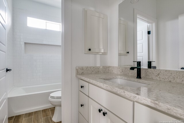 full bathroom featuring tiled shower / bath, toilet, and vanity