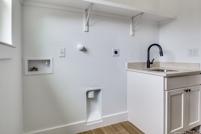 clothes washing area with cabinets, hookup for an electric dryer, light hardwood / wood-style floors, sink, and washer hookup