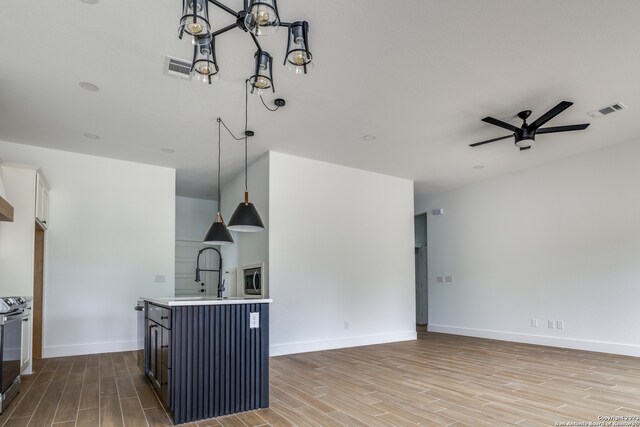 kitchen featuring hanging light fixtures, stainless steel appliances, ceiling fan, and light hardwood / wood-style flooring