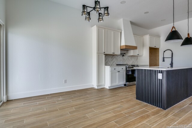 kitchen with stainless steel electric range oven, backsplash, premium range hood, and white cabinets