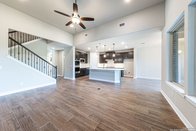 unfurnished living room featuring wood-type flooring, ceiling fan, and sink