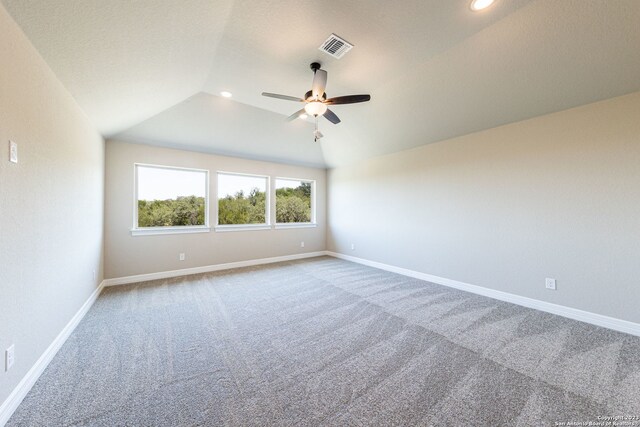 carpeted spare room featuring ceiling fan and vaulted ceiling