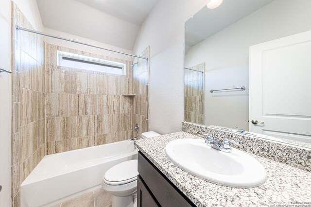 full bathroom with tiled shower / bath combo, toilet, vaulted ceiling, tile flooring, and vanity